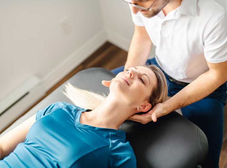 A chiropractor gently examining an adult patient's neck in a clinical setting.
