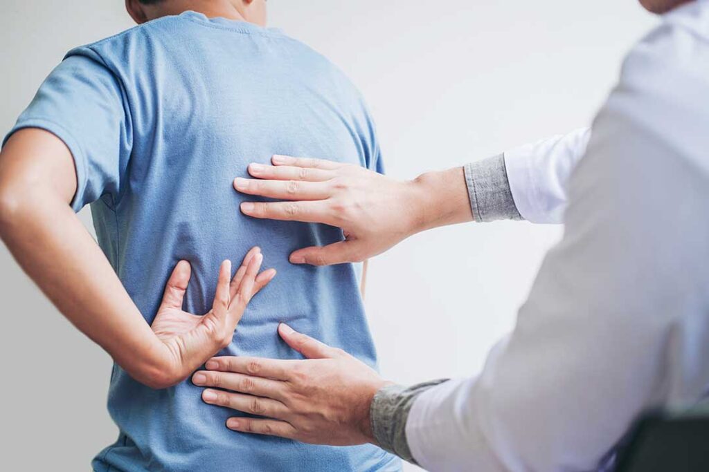 Person gently massaging the jaw while seated upright beside a window, with relaxed neck and shoulders.